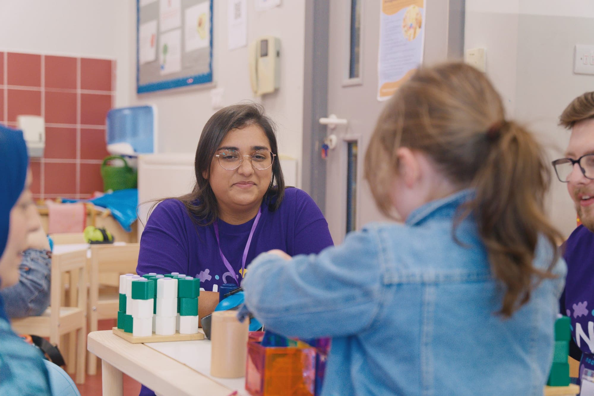 A Noa's Place team member supporting a child with stacking toys during sensory play